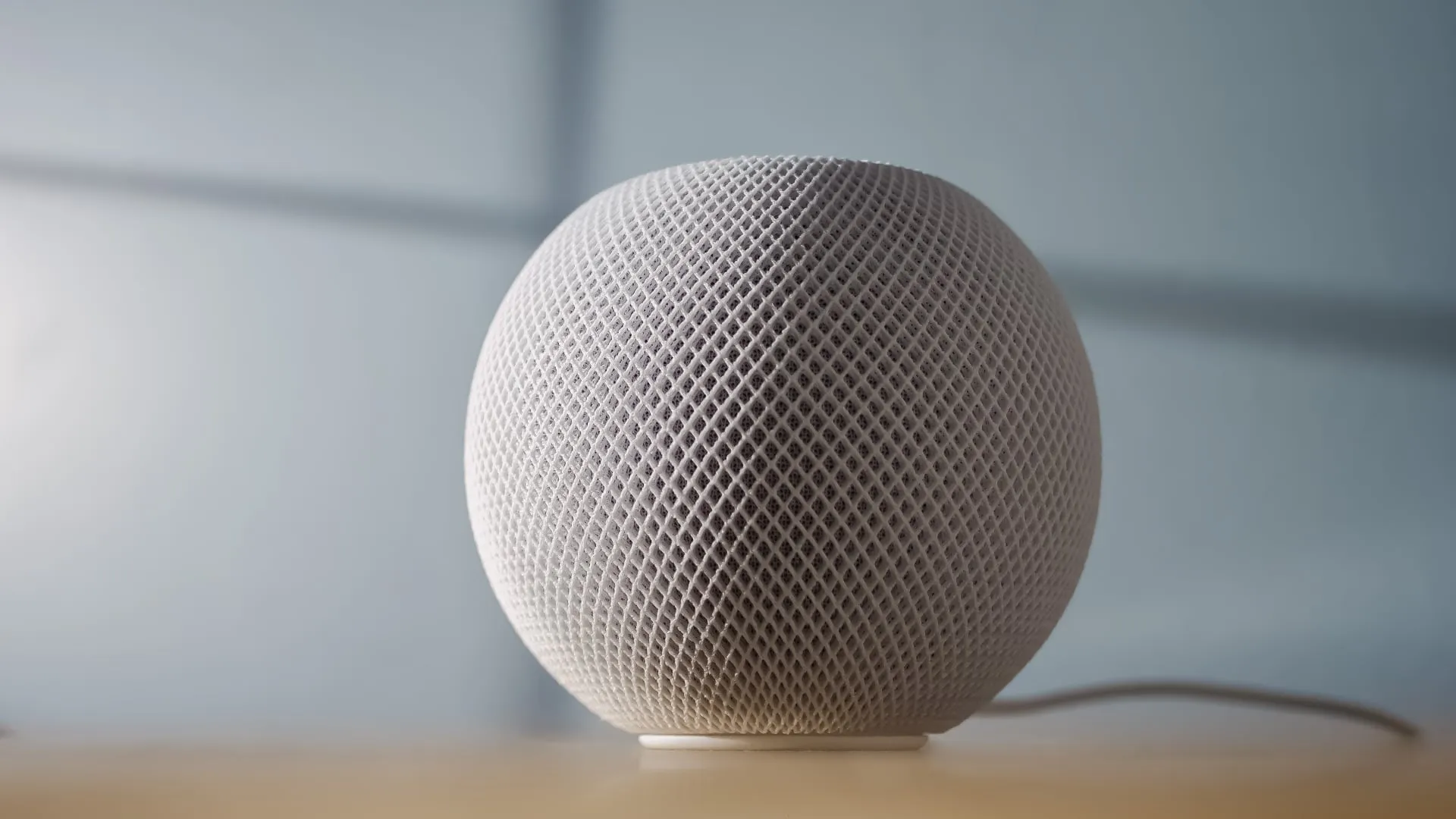 White HomePod mini set atop a wooden table