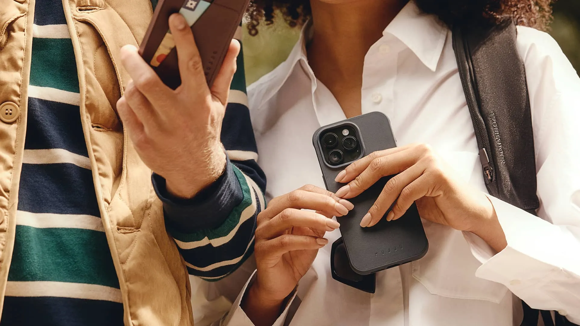 Mężczyzna i kobieta korzystający z iPhone'a 15 w skórzanym etui Mujjo