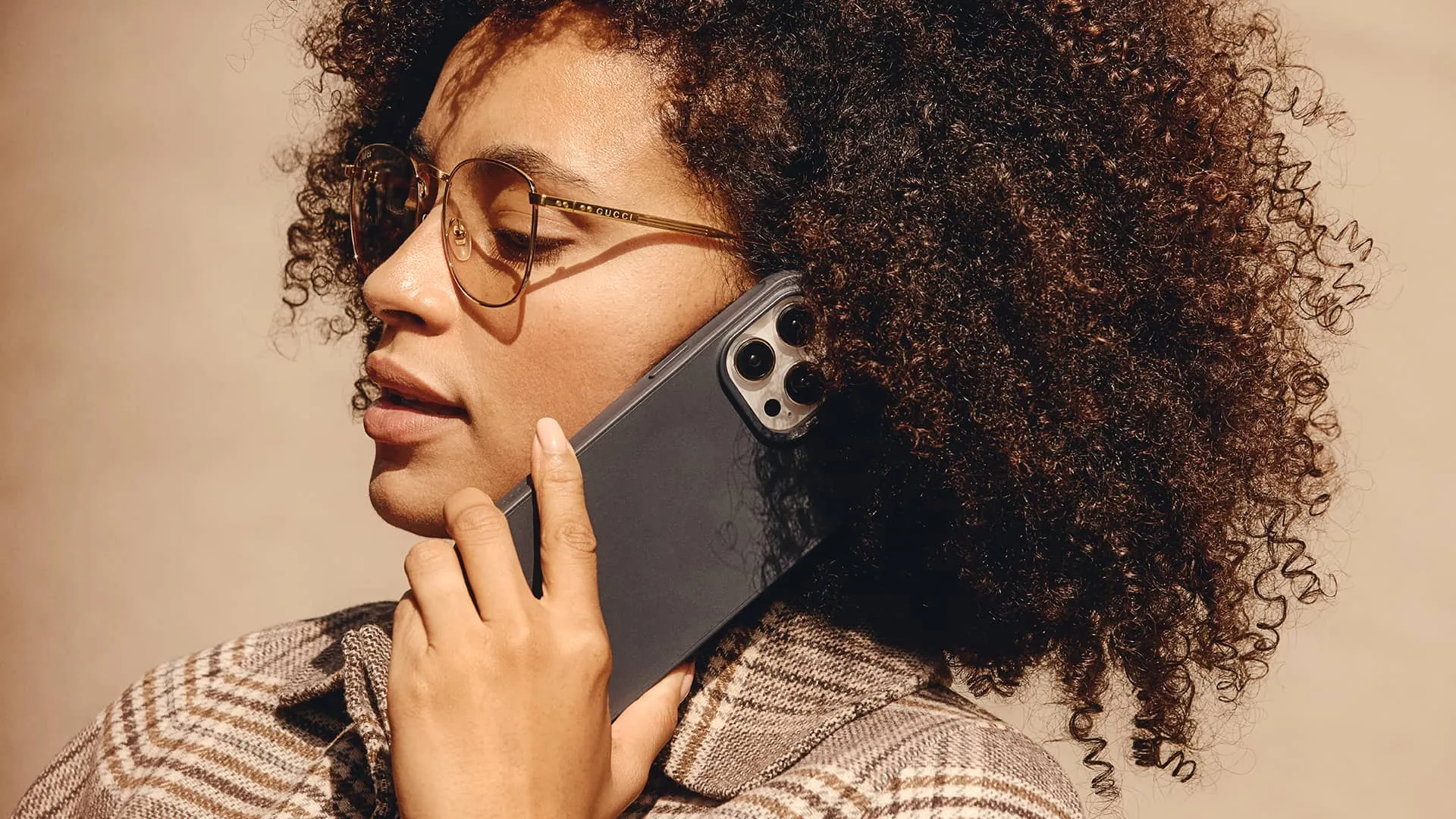 Young woman holding an iPhone 15 Pro in Mujjo's protective case against her ear