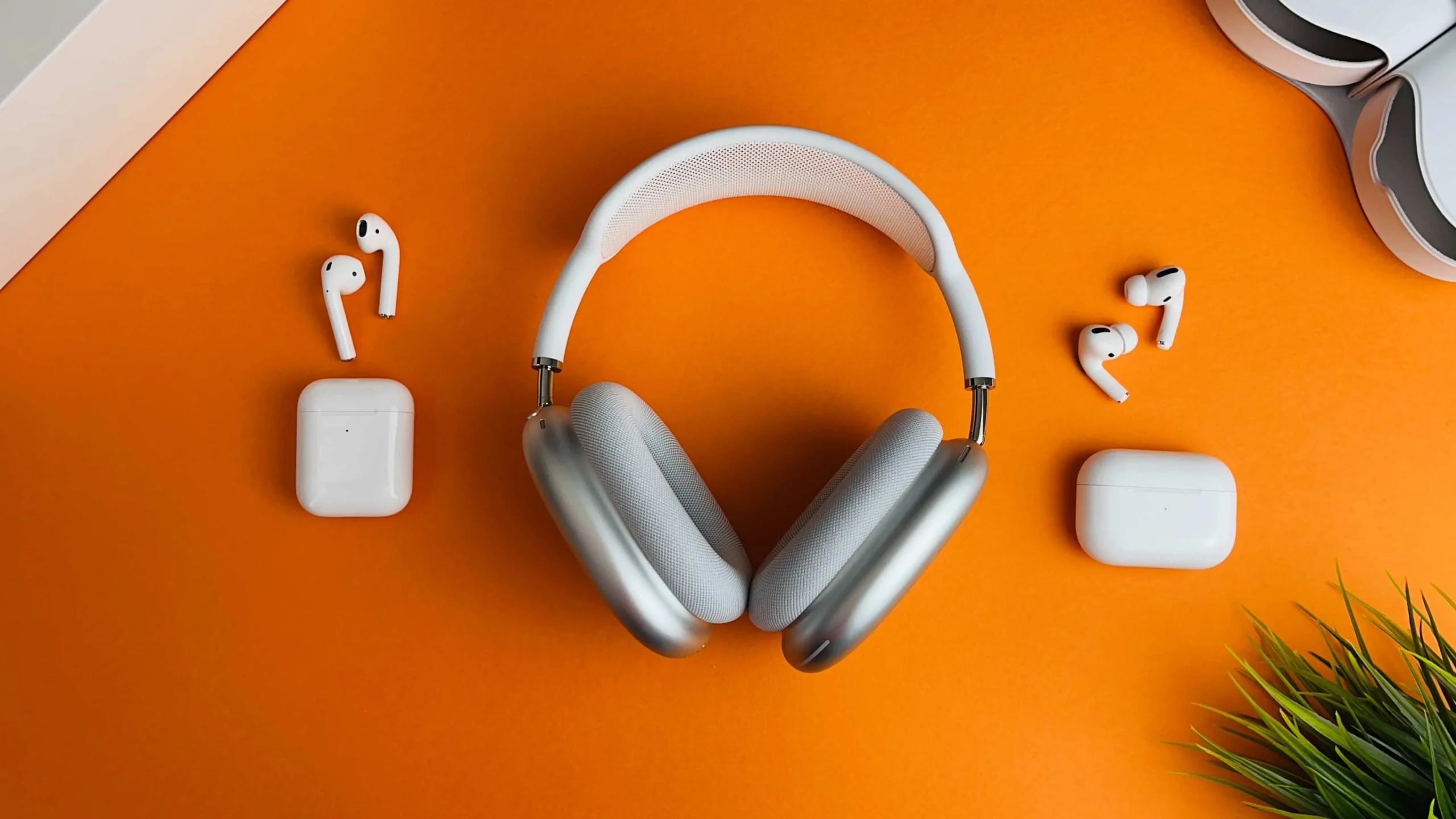 AirPods Max, os AirPods originais e o primeiro AirPods Pro colocados sobre uma mesa laranja