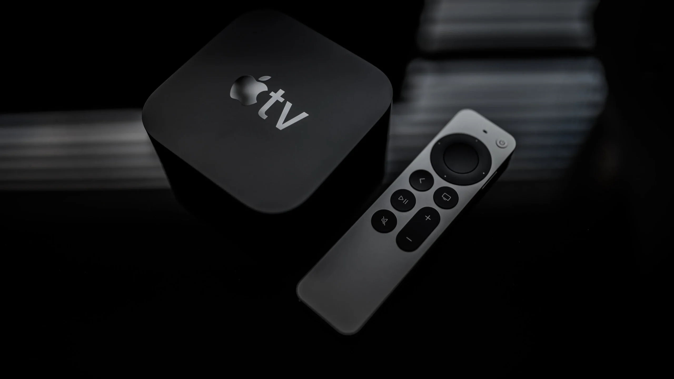 An angled top-down view of a second-generation Apple TV 4K along with an updated Siri Remote, set against a dark background An angled top-down view of a second-generation Apple TV 4K along with an updated Siri Remote, set against a dark background
