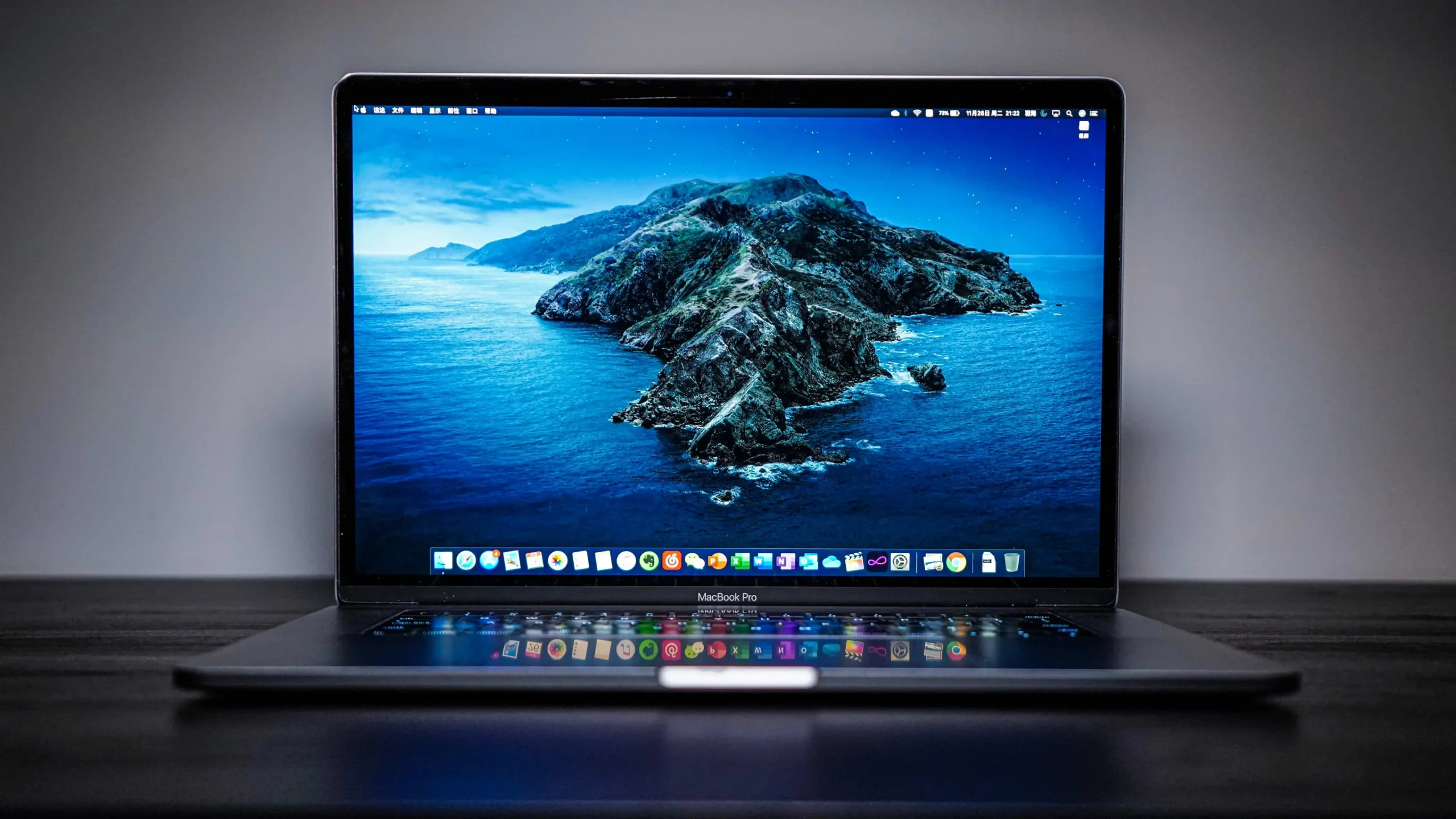 검은색 나무 책상 위에 뚜껑이 열려 있는 15인치 MacBook Pro