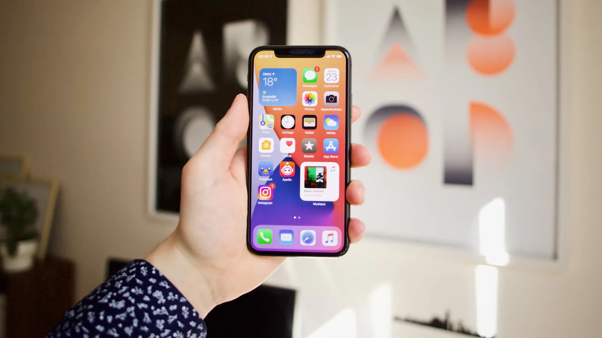 iPhone 14 Pro Max in de hand van een vrouw, tegen een muur met schilderijen