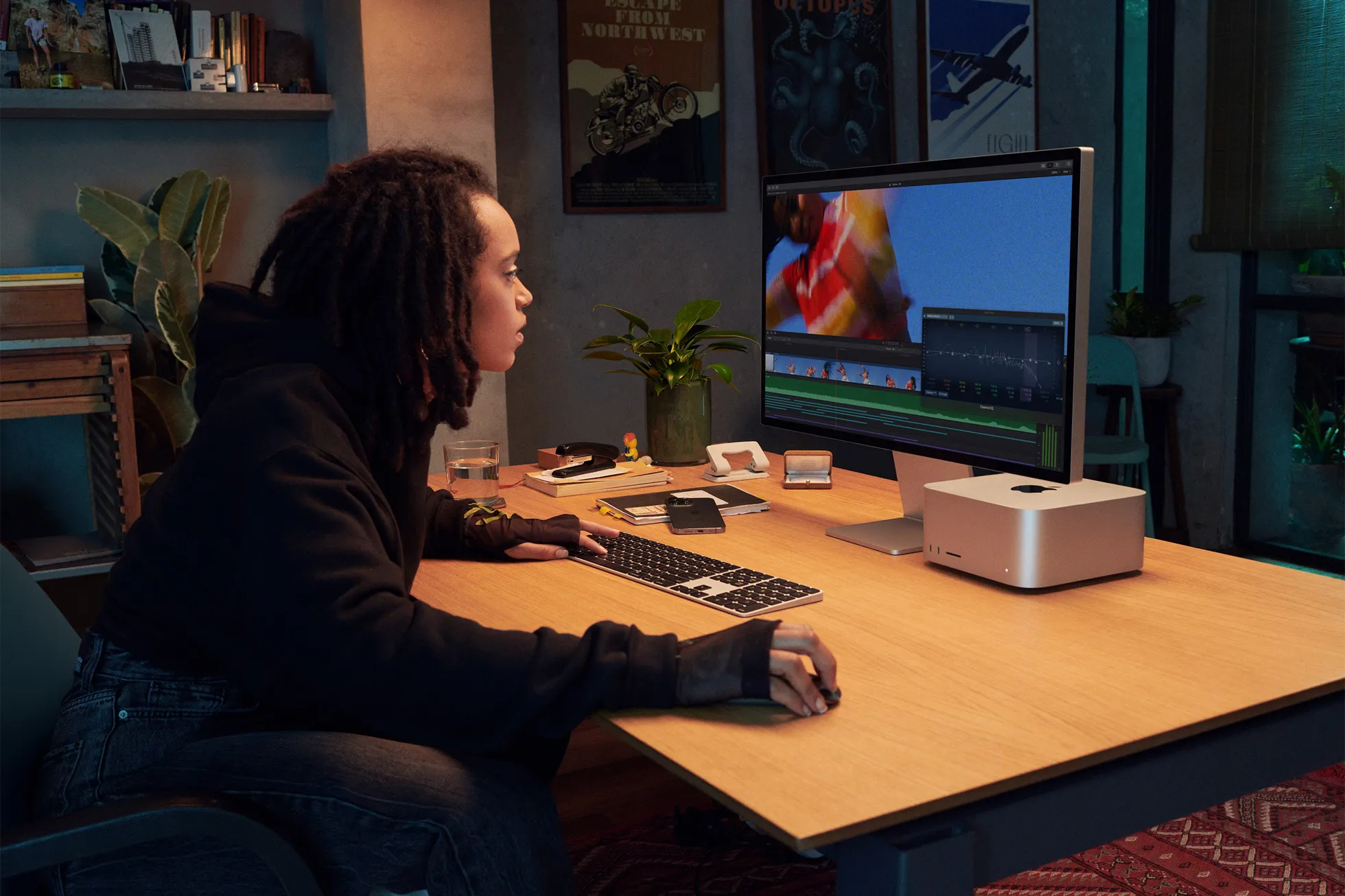 En esta imagen de marketing de Apple, se muestra a un profesional creativo sentado en su escritorio y usando una computadora Mac Studio conectada a un Studio Display.