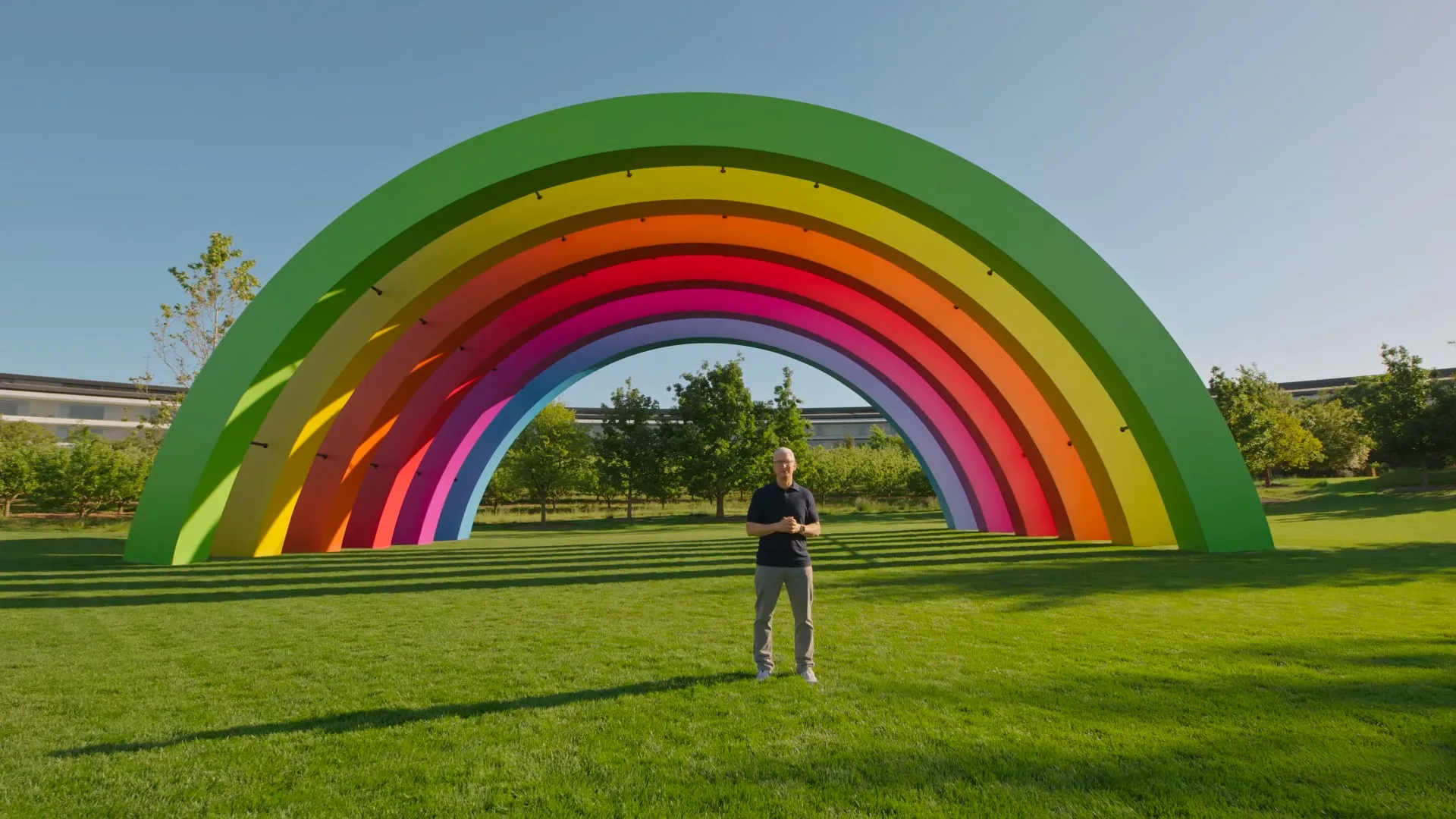 Tim Cook parado frente al escenario arcoíris del Apple Park