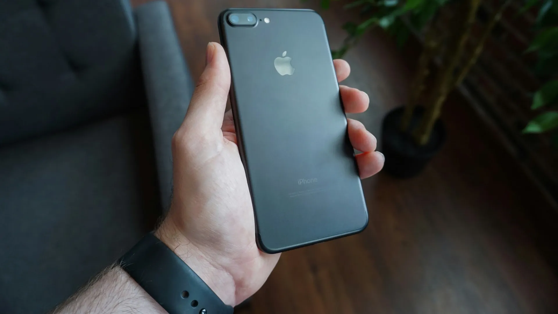 iPhone 7 Plus noir dans la main d'un homme, présentant le système de double caméra arrière