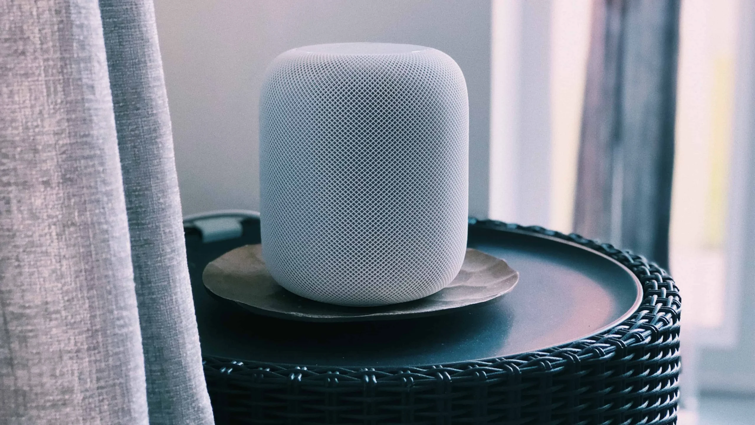 Op deze foto van Unsplash wordt een zilveren versie van de full-size HomePod draadloze luidspreker van Apple op een tafel getoond