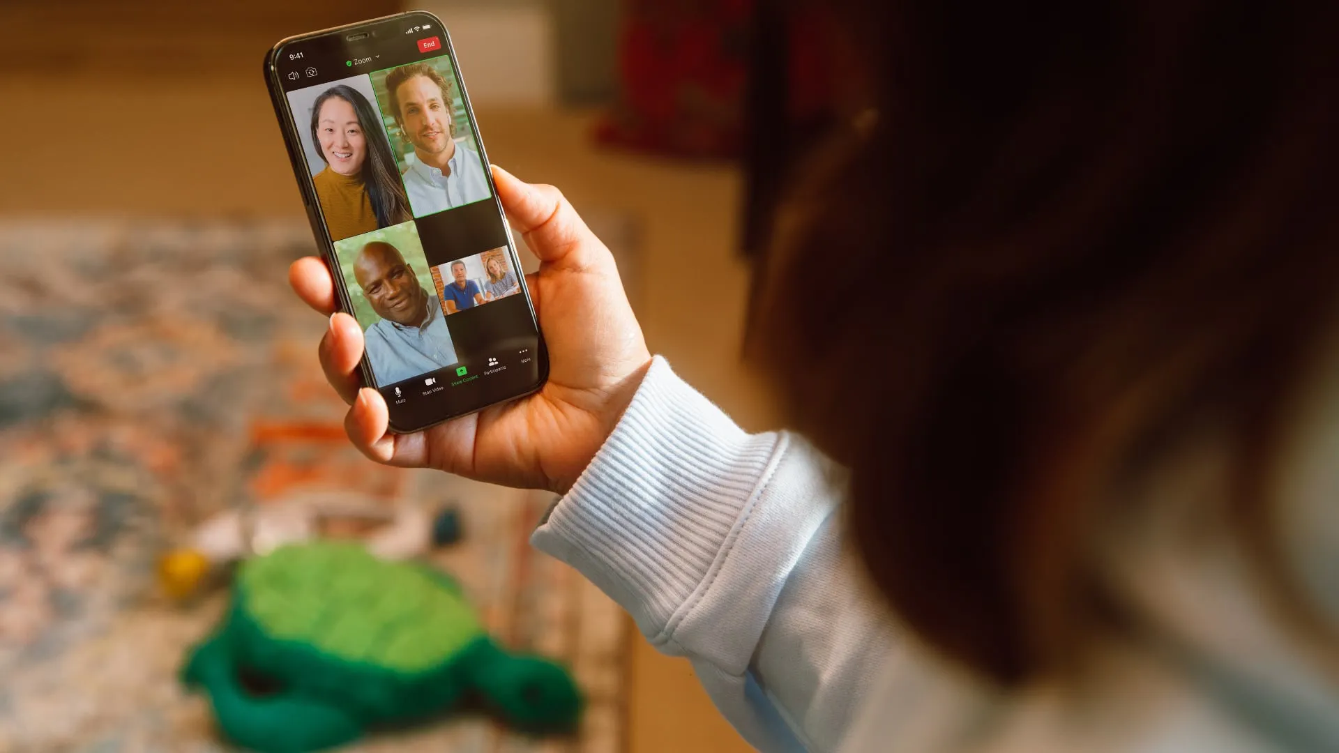 Femme dans un salon lors d’un appel vidéo Zoom sur son téléphone avec quatre autres personnes