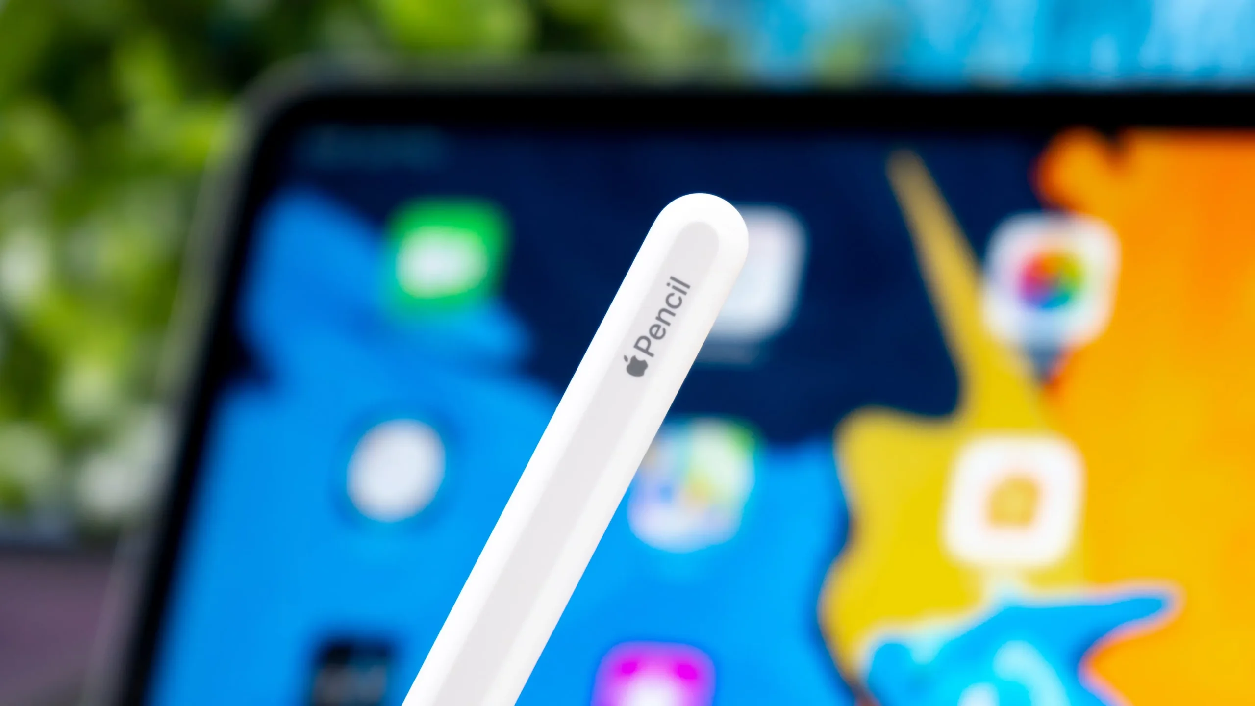 Gros plan montrant la fin de l'Apple Pencil avec la marque, avec un iPad Pro flou en arrière-plan